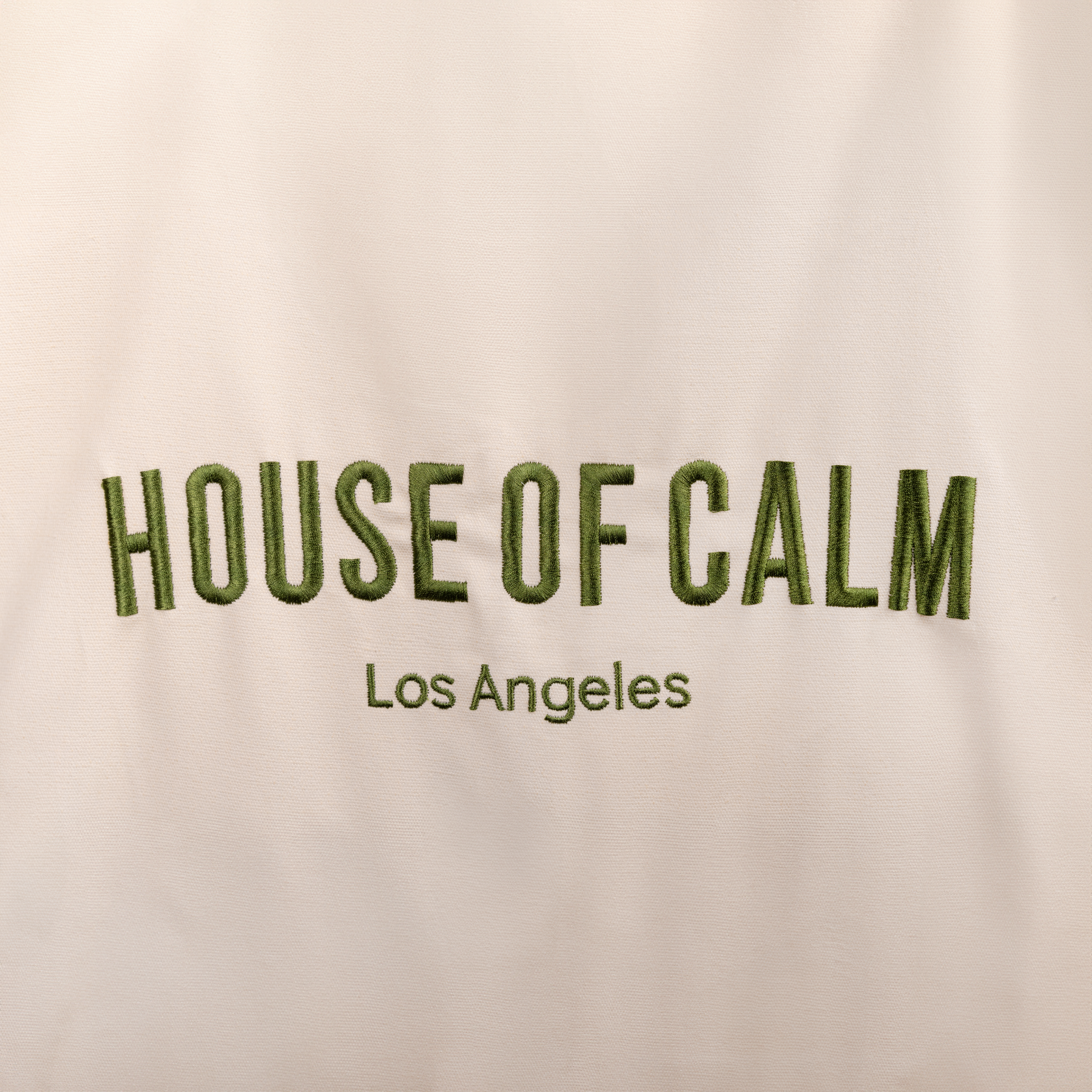Close-up of embroidered House of Calm logo on natural cotton tote bag