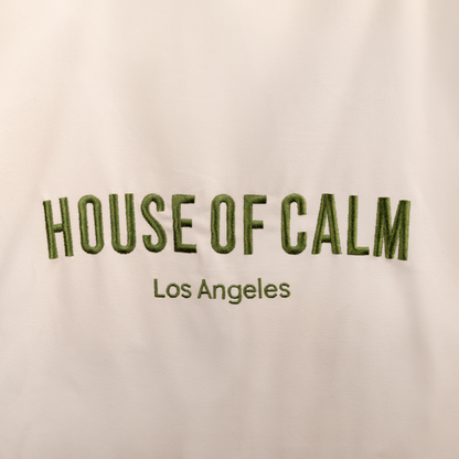 Close-up of embroidered House of Calm logo on natural cotton tote bag