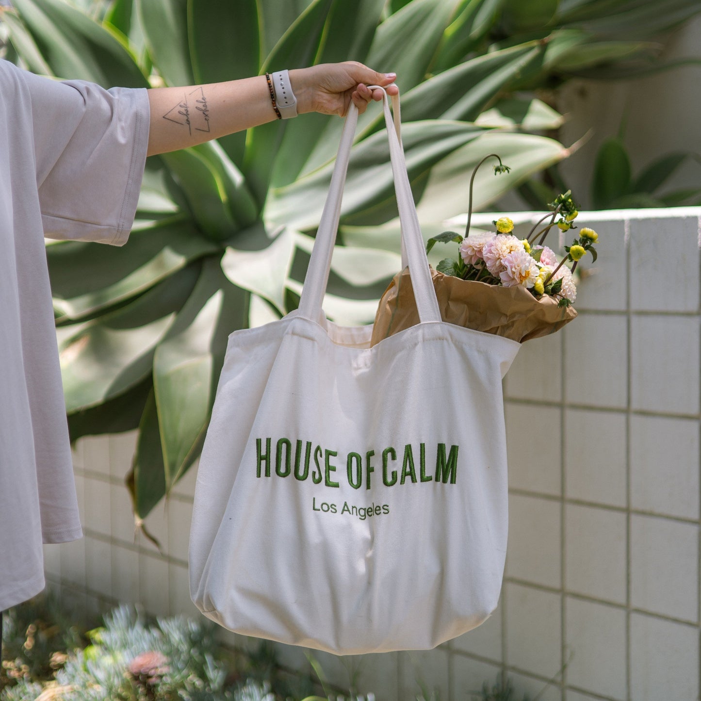 House of Calm tote bag filled with flowers and vegetables at farmers market